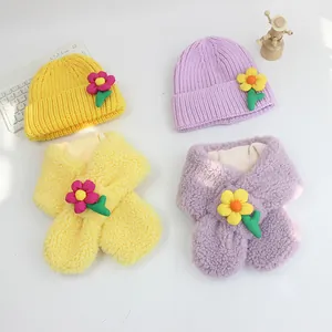 Detailansicht von Kinder-Strickmützen und Plüschschals mit floralen Verzierungen