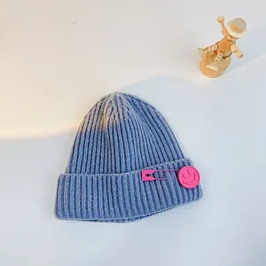 Blue-purple cable knit toddler beanie featuring a pink smiley face pin detail