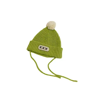 Green knit baby beanie with faux fur pompom and earflaps for autumn winter warmth