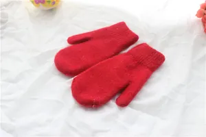 Nahaufnahme roter Strickfäustlinge aus Kaninchenfell auf weißem Stoff mit Blumen