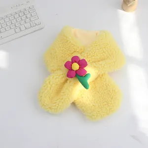 Detail eines gelben Plüschschals mit einer rosa Zierblume für Kinder im Winter