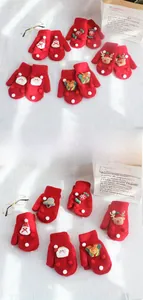 Detail of red Christmas knit gloves featuring 3D Santa, reindeer, and tree ornaments