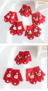 Close-up of red knitted Christmas mittens for kids featuring festive 3D cartoon ornaments