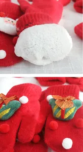 Detail of red knitted Christmas gloves with thick fleece lining and gift box embroidery