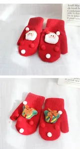 Detail of red knitted Christmas gloves with 3D Santa Claus and gift box patterns