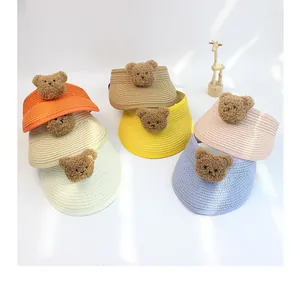 Detailed close-up showing colorful woven straw sun hats with cute 3D plush bear patches