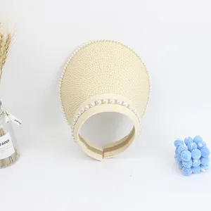 Detail of cream straw visor hat with elegant pearl embellishments and woven texture