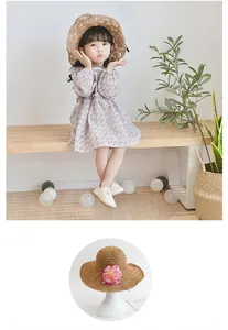 Close-up of children's woven straw sun hat with delicate pink floral decorations