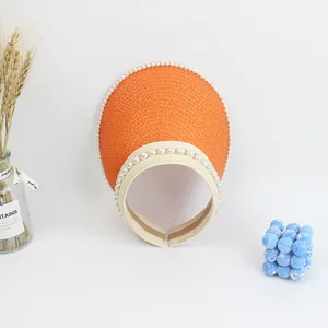 Detail view of the orange straw woven sun visor with elegant white pearl trim decorations