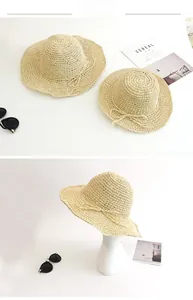 Detail of beige hand-woven straw hats for parent and child with elegant bow accents