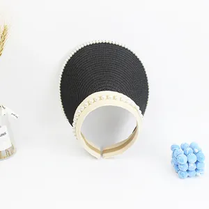 Detail of elegant black and white straw visor with pearl trim and headband design