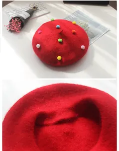 Detail eines roten Woll-Baskenmützen mit bunten Pompons und dicker Filzstruktur