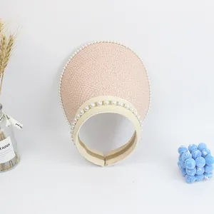Detail of pink straw sun visor with pearl accents and elastic band for women and kids