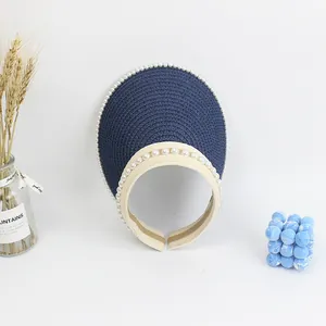 Detail of straw woven visor hat with elegant pearl embellishments and blue texture