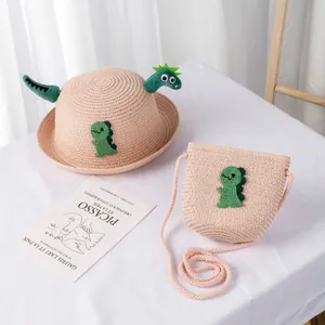 Dettaglio cappello di paglia rosa e borsa coordinata con ricamo di dinosauro verde