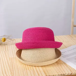 Dettaglio di cappelli di paglia intrecciati a mano in rosa e beige su un tavolo