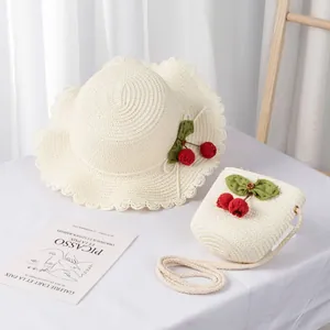 Detail of kids straw sun hat and matching cherry bag set in creamy white finish