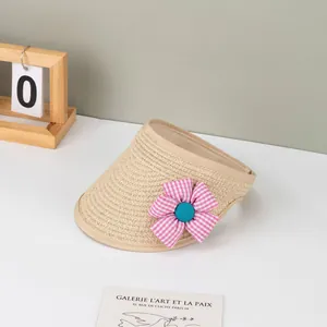 Detail eines beigen Stroh-Sonnenvisiers mit rosa karierter Blume und hellblauem Knopf
