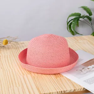 Cappello di paglia intrecciata rosa con cupola rotonda su un tavolo in legno