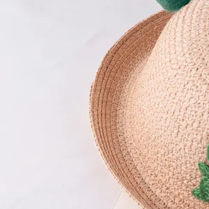 Dettaglio della paglia intrecciata e decorazione a foglia verde su un cappello da sole bimbi