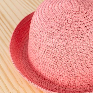Dettaglio del cappello di paglia rosa con trama a spirale fitta e finitura estiva