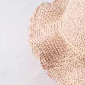 Detail of pink straw sun hat featuring a wavy scallop edge and woven texture for girls