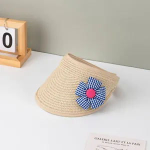 Detailansicht eines beigen Stroh-Sonnenhutes mit blau-karierter Blume und rosa Knopf