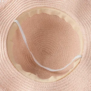 Detail view of pink straw hat interior with sweatband and elastic windproof strap