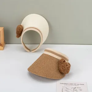 Summer kids straw visor hat with bear pom pom decoration in beige and brown colors