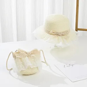 Detail of girls' cream straw sun hat and matching bag with lace trim and bow