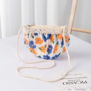 Detalle de bolso bandolera de gasa floral con encaje crema y correa de cuerda