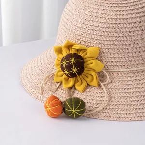 Girls straw sun hat with decorative sunflower and hanging pom-poms for summer beach trips