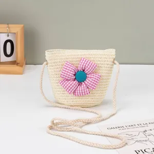 Detail der geflochtenen Kinder-Strohtasche mit einer rosa karierten Stoffblumenverzierung