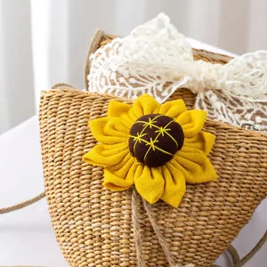 Detail of woven straw bag featuring sunflower decor and white lace bow for kids
