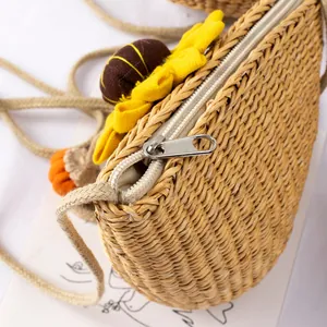 Close-up of woven straw crossbody bag with metal zipper and sunflower detail