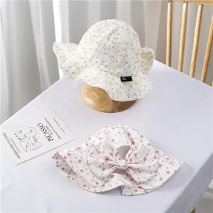 Detailed view of floral cotton sun hats with wide wavy brims and a large pink bow tie