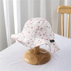 Detailed texture of baby floral sun hat with pink petals and white elastic wind strap