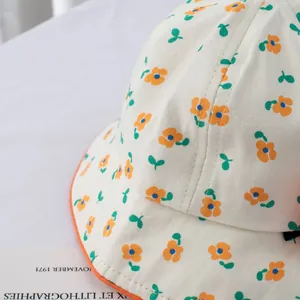 Detail of floral pattern baby sun hat with orange binding and soft cotton texture