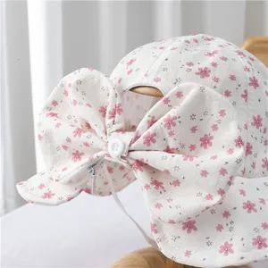 Detail of floral baby sun hat featuring a large bow, zipper pocket, and windproof strap