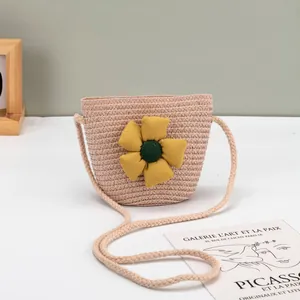 Detail einer rosa geflochtenen Stroh-Umhängetasche mit einer großen gelben Stoffblume