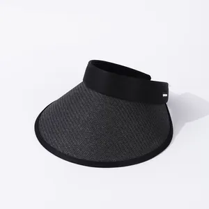 Detalle de la visera de paja negra con un elegante adorno de hebilla metálica
