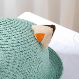 Close-up of mint green woven straw hat featuring cute embroidered cat ear details