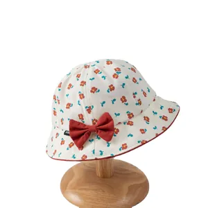 Floral baby sun hat with red bow and small flower pattern on a wooden stand