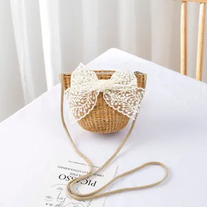Detail of straw woven crossbody bag featuring a large white lace bow and shoulder strap