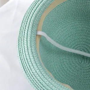 Close-up of mint green straw hat interior featuring fine weave and elastic chin strap