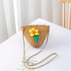 Detail of hand-woven straw bag with a yellow flower and a long braided strap