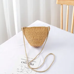 Detailed close-up of handmade straw woven crossbody bag with zipper and rope strap