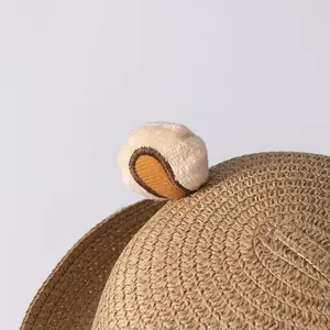 Detail van een kinderstrohoed met pluche berenoren en fijne spiraalvormige weving