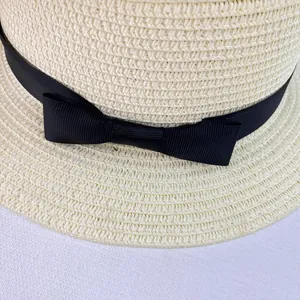 Close-up of woven straw hat featuring a black ribbon bow and fine texture detail