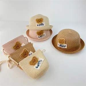 Detailed macro view of woven straw kids sun hat and matching bag with cute bear patches